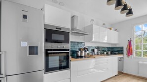 A modern kitchen with stainless steel appliances, white cabinetry, and a window providing natural light.