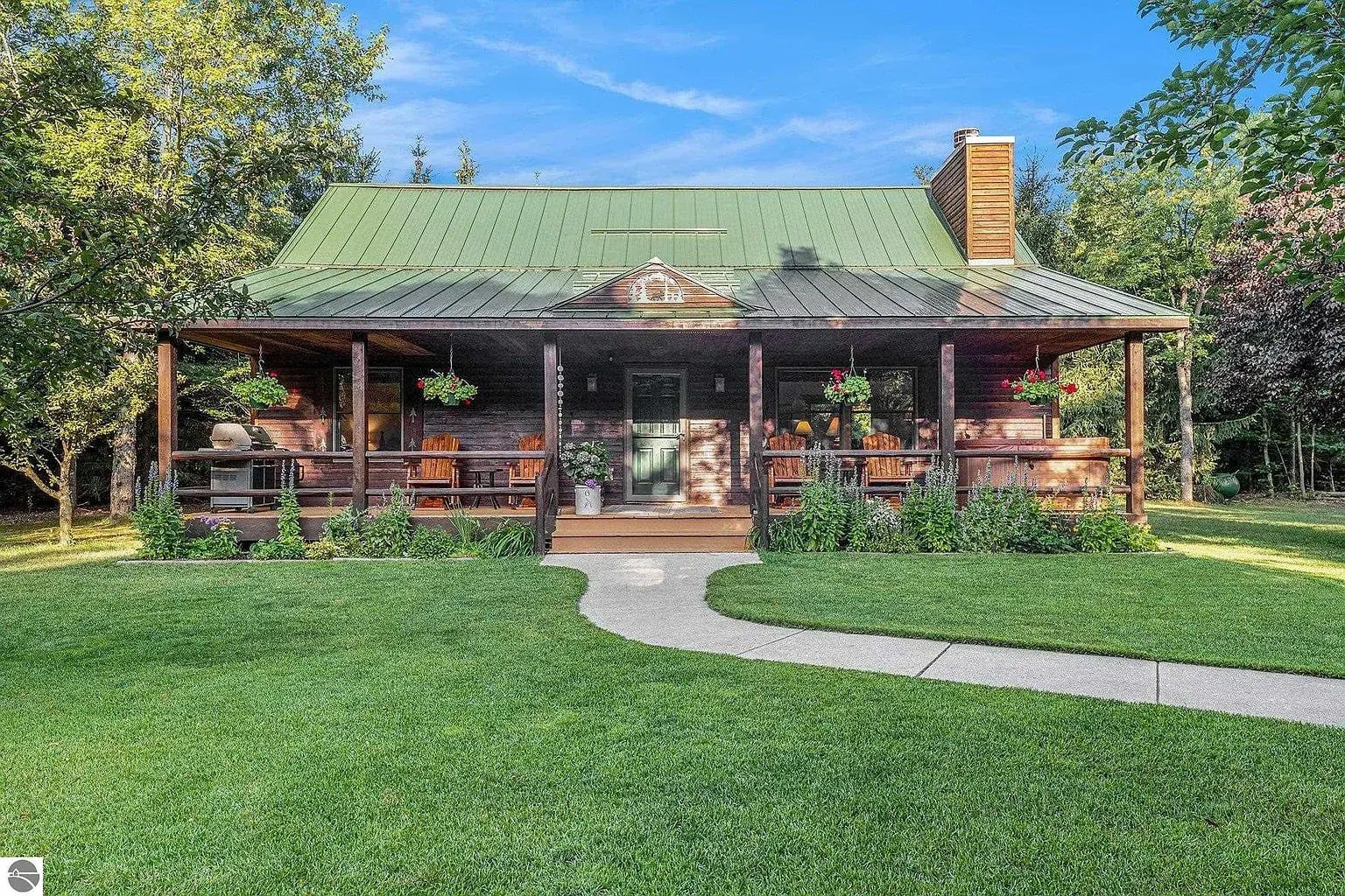 A rustic cabin with a covered porch, a chimney, and a well-maintained lawn.