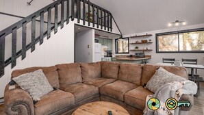 En moderne stue med en brun hjørnesofa, et træsofabord og en trappe med sorte gelændere.