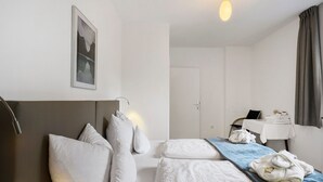 A hotel room with a bed, pillows, a towel, a desk with a laptop, and a door. - Room 'Haus Burger Vilpian  4' with Mountain View and Wi-Fi (Vilpiano)
