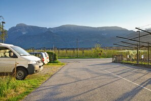 Un parking avec une rangée de voitures, une clôture et des montagnes en arrière-plan.