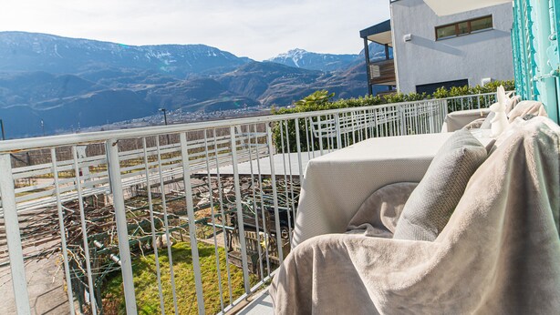 A balcony with a view of mountains, a white railing, and a covered seating area. - Room 'Haus Burger Vilpian  4' with Mountain View and Wi-Fi (Vilpiano)