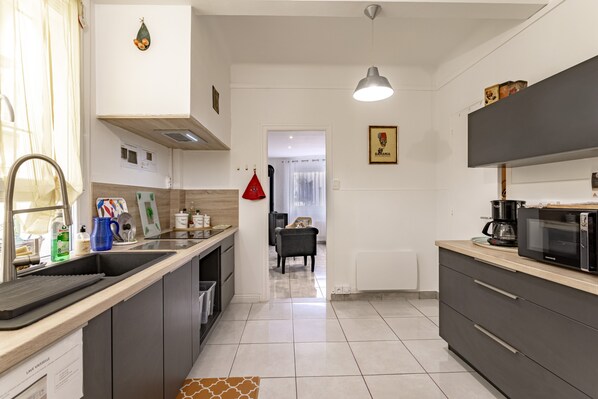 A modern kitchen with a sink, countertop, microwave, and cabinets.