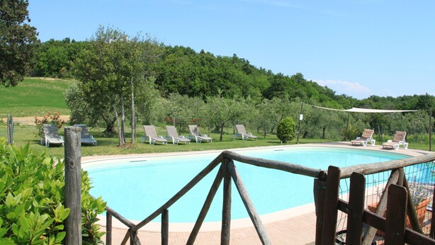 Un área de piscina con sillas de descanso y una valla de madera.