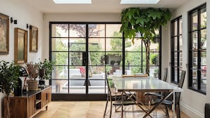 Una habitación amplia con un gran ventanal, una mesa de comedor y una planta en maceta.