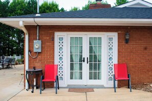 A brick building with a white door and two red chairs outside. - National Harbor Suite 2 (Fort Washington)