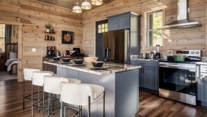 Una cocina moderna con paredes de madera, electrodomésticos de acero inoxidable y una isla central con taburetes de bar.