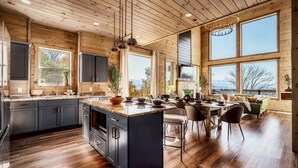 Una cocina amplia con armarios de madera, una isla grande y abundante luz natural proveniente de ventanas amplias.