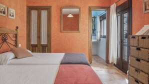 A bedroom with a bed, a mirror, a wardrobe, and a view of the outside. - Holiday Home 'De Bárbara' with Balcony and Air Conditioning (Alcalá de los Gazules)
