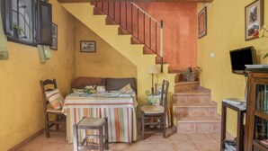 A cozy room with a staircase, a dining area with a table and chairs, and a television on a stand. - Holiday Home 'De Bárbara' with Balcony and Air Conditioning (Alcalá de los Gazules)