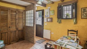 A room with wooden doors, a table with papers, a window with a plant, and a radiator. - Holiday Home 'De Bárbara' with Balcony and Air Conditioning (Alcalá de los Gazules)