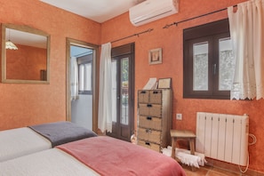 Une chambre avec deux lits, un radiateur, une fenêtre avec des rideaux, un miroir et un climatiseur fixé au mur.