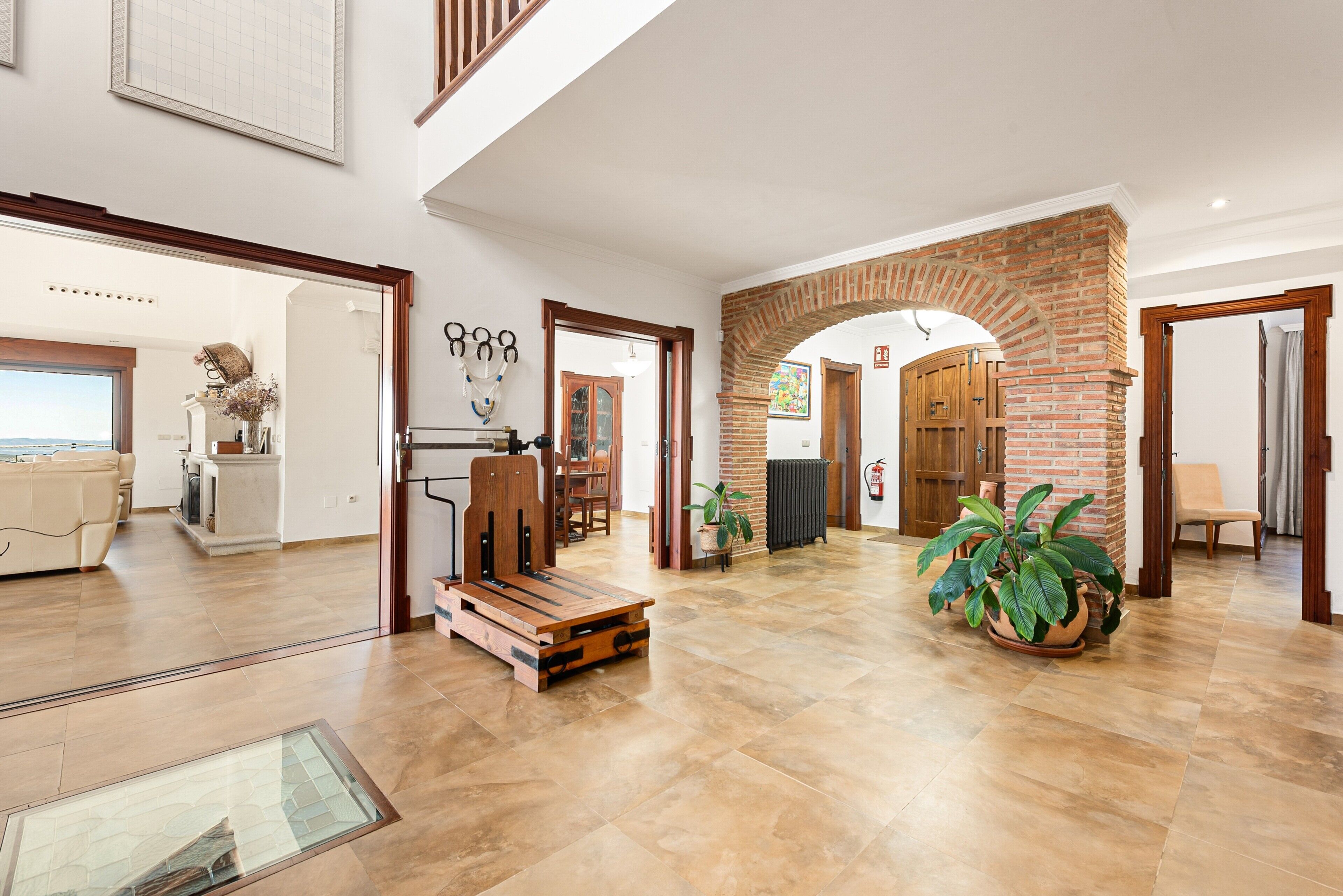 A spacious living area with a large window, a wooden bench, and a potted plant.