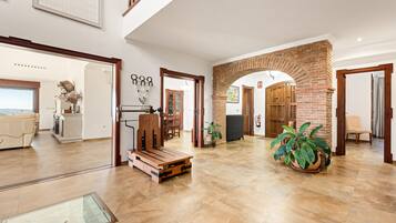 A spacious living area with a large window, a wooden bench, and a potted plant.