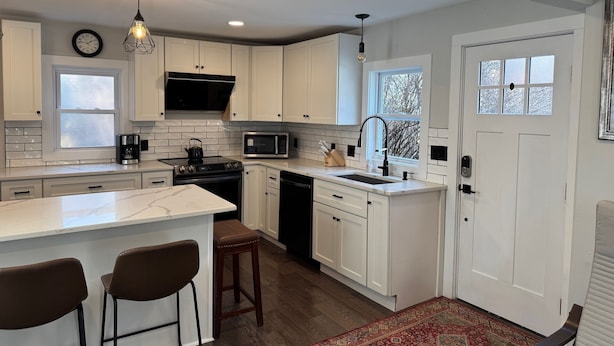 A modern kitchen with white cabinets, a central island, a microwave, and a stove.