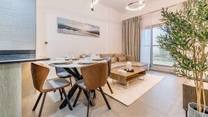 A modern living room with a dining area, a large window, and a potted plant.