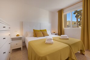 Une chambre d’hôtel avec un lit, des tables de chevet, une armoire et une fenêtre avec des rideaux.