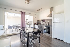 Une cuisine moderne avec un coin repas, un réfrigérateur et une vue à travers la porte vitrée.