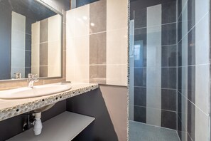 Un baño con lavamanos, espejo y paredes de azulejos.