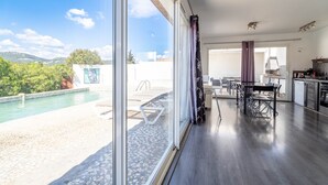 A modern living room with a large window, a pool, and a dining area. - Villa 'Piscine Privée Proche Plages' with Private Pool, Private Terrace and Wi-Fi (Montséret)