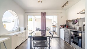 A modern kitchen with a dining area, a large window, and a view of the outdoors. - Villa 'Piscine Privée Proche Plages' with Private Pool, Private Terrace and Wi-Fi (Montséret)