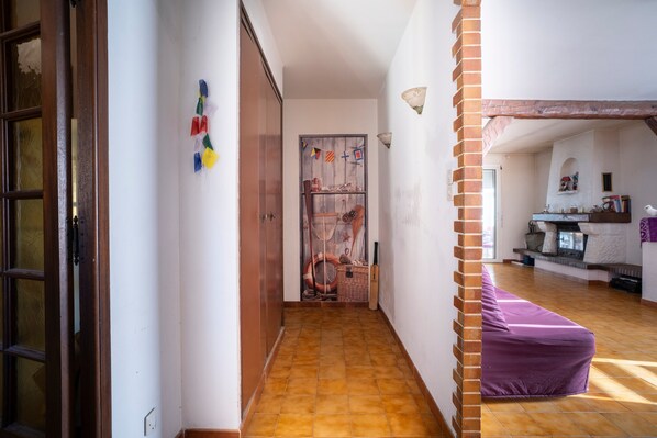 Un pasillo con piso de baldosas, una puerta de madera y un sofá púrpura en el comedor.