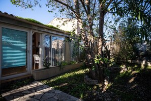 Una casa con puerta corrediza de vidrio, un sendero de piedra y un árbol en el jardín.