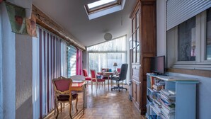 Une pièce avec un plancher en bois, une table à manger avec des chaises, un téléviseur et une bibliothèque.
