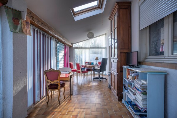 Una habitación con piso de madera, una mesa de comedor con sillas, un televisor y una estantería.
