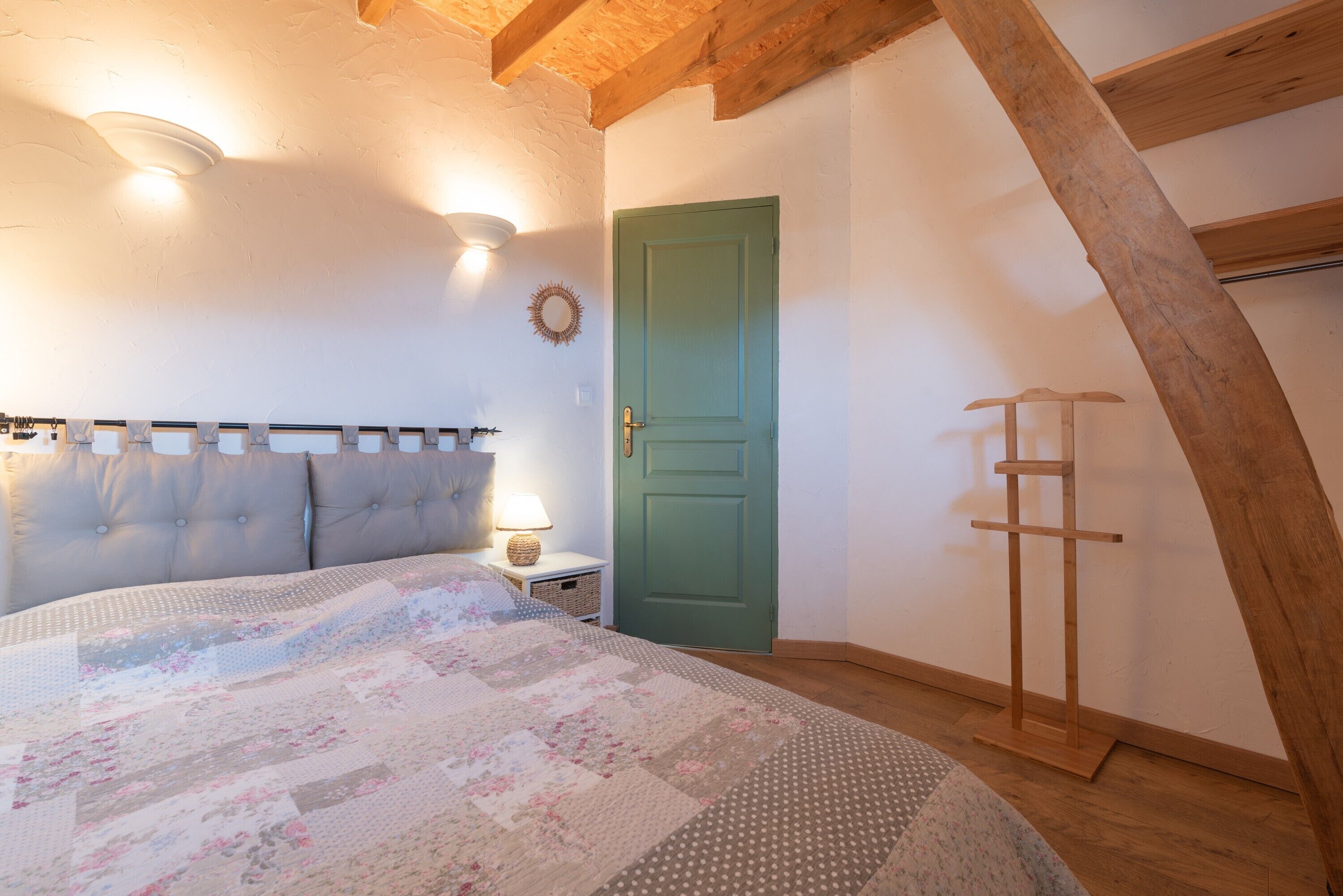 Une chambre à coucher avec un lit, une porte verte, une échelle en bois et une tête de lit dotée de lumières.