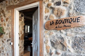 A stone building with a wooden sign reading 'LA BOUTIQUE de Jean-Marie' and a doorway leading inside.