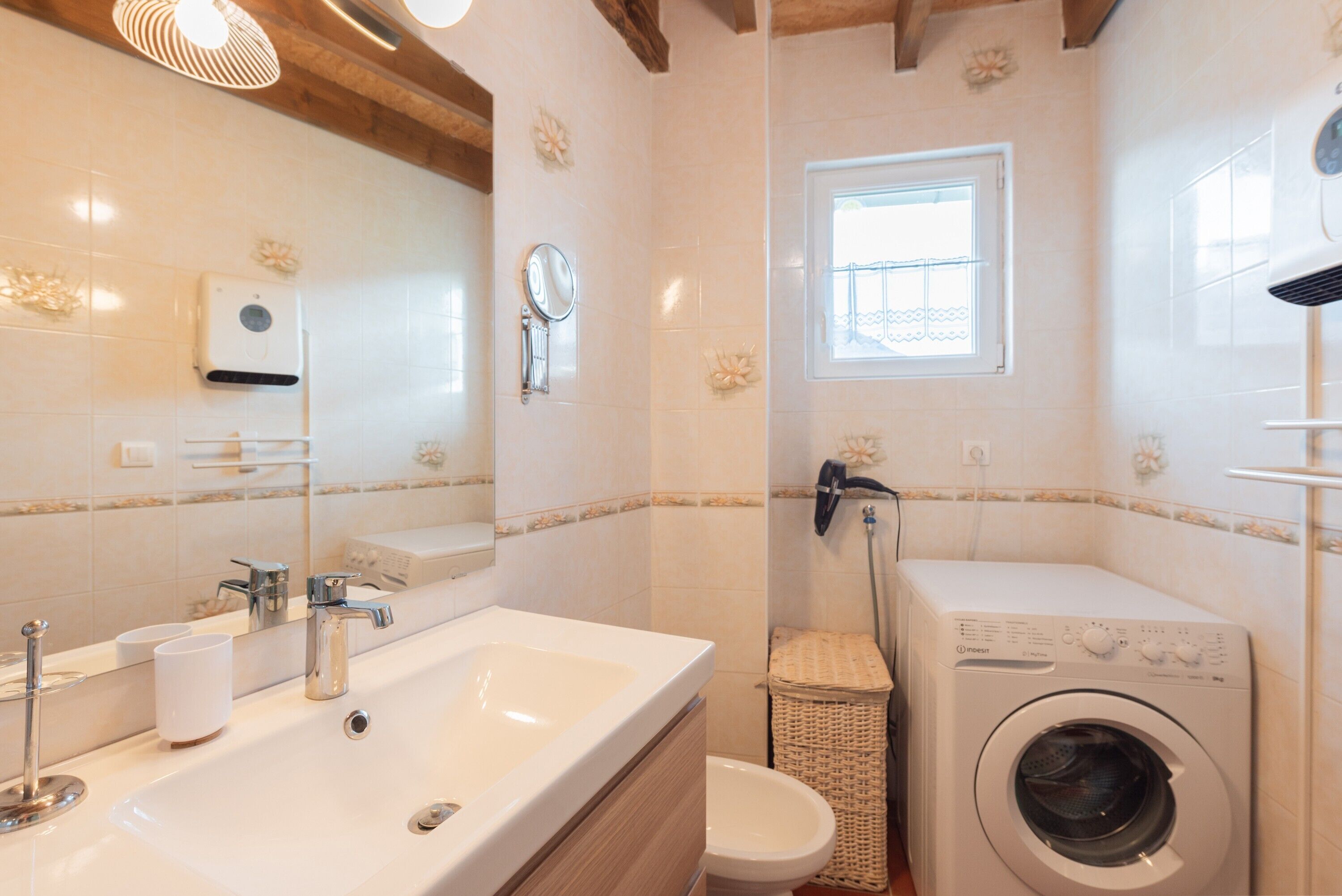 Ein Badezimmer mit Waschbecken, Spiegel und Waschmaschine.