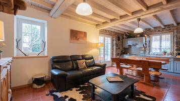 Ein rustikales Interieur mit einer Ledersofa, einem Holzesstisch und einem Kuhfellteppich.
