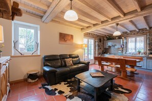 A rustic interior with a leather sofa, wooden dining table, and a cowhide rug.