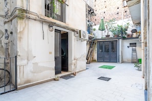 A narrow alleyway with a building entrance, a bicycle, and potted plants.