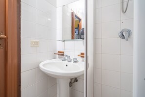 A bathroom with a white sink, mirror, and shower.