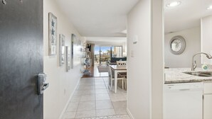A modern kitchen with a built-in dishwasher, a dining area with a table and chairs, and a view of the outdoors.