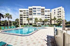 A hotel with a swimming pool, multiple balconies, and a tiled deck area. - Surf & Racquet B122 - Hosted by Moore AI Rentals (Fernandina Beach)