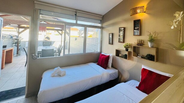 Una habitación de hotel con dos camas, un ventanal grande y vista al patio exterior.