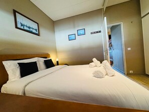 A hotel room with a bed, a nightstand, a wall-mounted picture, and a door leading to another room. - Apartment 'Casa Azul' with Private Terrace, Private Garden and Wi-Fi (Torreira)