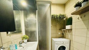 Un baño pequeño con lavabo, espejo, lavadora e inodoro.