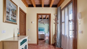 Un pasillo con techo de madera, una cama con colcha a rayas, un armario de madera y un cuadro en la pared.