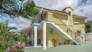 A two-story house with a balcony, a staircase, and potted plants. - Holiday Home 'Palati' with Sea View, Wi-Fi and Air Conditioning (Kefalonia)