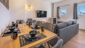A modern dining area with a wooden table set for a meal, a gray sofa, and a TV mounted on the wall. - Apartment '42A' with Mountain Views, Private Terrace and Wi-Fi (Sierra Nevada)