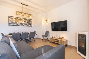 A modern living room with a sofa, chairs, a dining table, a TV, and a fireplace. - Apartment '42A' with Mountain Views, Private Terrace and Wi-Fi (Sierra Nevada)