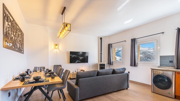 A modern living room with a dining area, a gray sofa, a flat-screen TV, and a washing machine. - Apartment '42A' with Mountain Views, Private Terrace and Wi-Fi (Sierra Nevada)