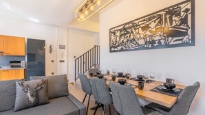 A dining area with a wooden table set for six, grey upholstered chairs, and a black and white abstract painting on the wall. - Apartment '42A' with Mountain Views, Private Terrace and Wi-Fi (Sierra Nevada)