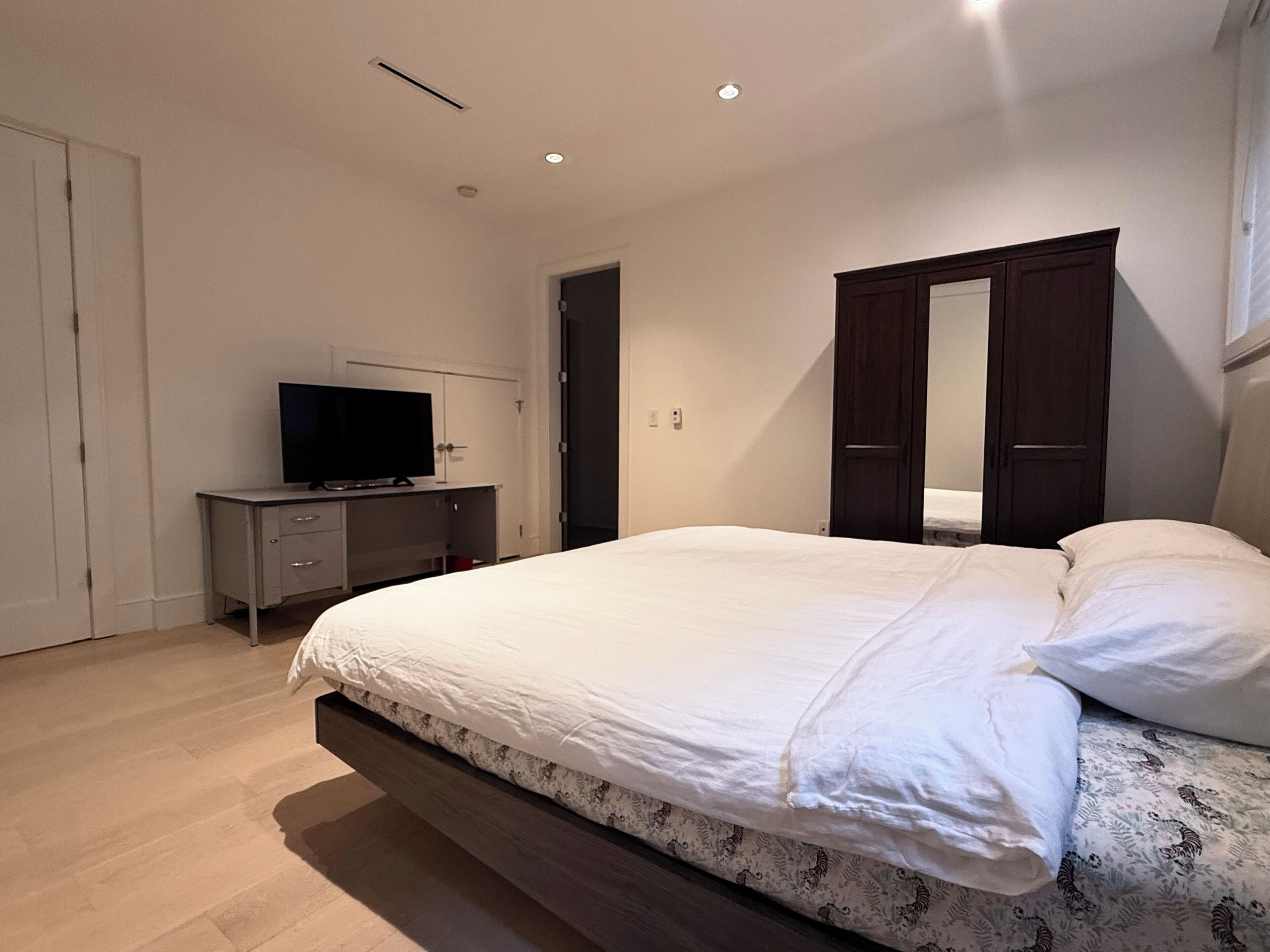 A bedroom with a bed, a TV on a desk, and a wardrobe.