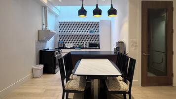 A modern kitchen with a central island, black chairs, and pendant lighting.
