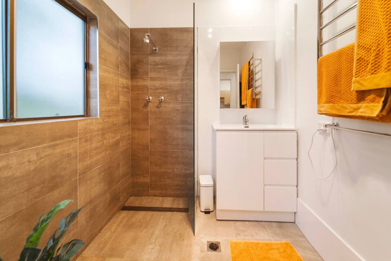A modern bathroom with a shower, a sink, and a mirror.